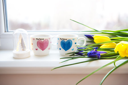 beautiful flowers-tulips and irises lie on the windowsill with two cups of coffee.の写真素材