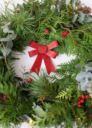 Stylish Christmas wreath for the interior. Handmade wreath with a beautiful red bow. Celebration atmosphereの写真素材