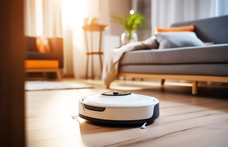 A modern robot vacuum cleaner works in a modern room. Beautiful light from the windowの素材