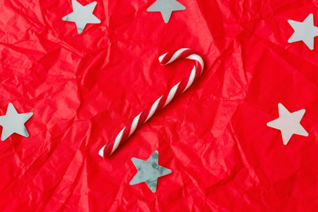 This is a bright and colorful Christmas background with white stars, a candy cane, and a crumpled textureの写真素材