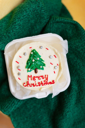 A festive Christmas cupcake with a green tree and red Merry Christmas text on a white frostingの写真素材