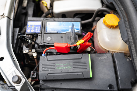 car engine with a diagnostic tool attached. The tool is a small black box with a red and black wire attached to it. The tool is connected to the car battery and the engineの写真素材
