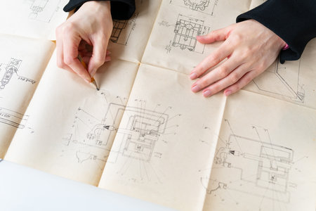 This image shows hands reviewing architectural blueprints for construction or renovation. The plans are detailed and contain various designs and layouts for a building or structureの写真素材