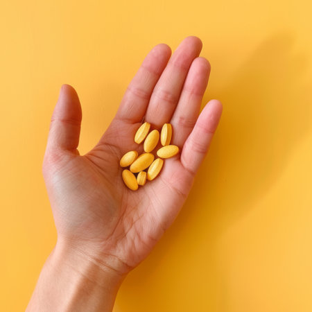 A hand holds bright vitamins on a bright orange background. Taking care of health, supporting the bodyの素材