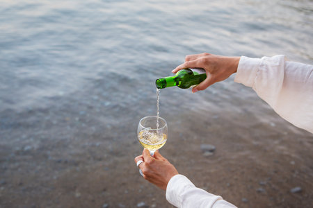 Picnic near the sea, a girl pours wine against the backdrop of the sea. Romance, date