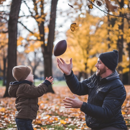Smiling father catching a football in a park during the vibrant autumn seasonの素材