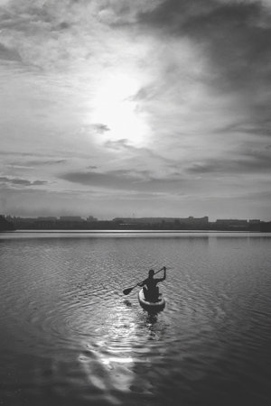 The girl paddles on the water to meet the sunrise. Stand up kayaking or stand-up paddleboarding on a...