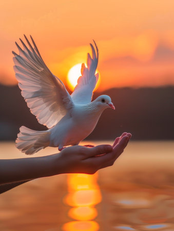 The silhouette of a hand and a dove are set against a twilight sky, the bird in mid-flight. The image captures a moment of letting go and beautyの素材