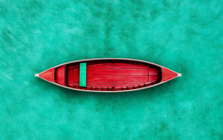 Red boat on turquoise ocean water - top view of vibrant wooden vessel.の素材