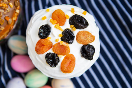 A delicious Easter kulich, a traditional sweet bread, is adorned with a creamy topping, dried apricots, and prunes. Perfect for Easter celebrations and festive baking.の写真素材