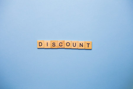 Wooden blocks spelling out the word 'DISCOUNT' on a light blue background.の写真素材