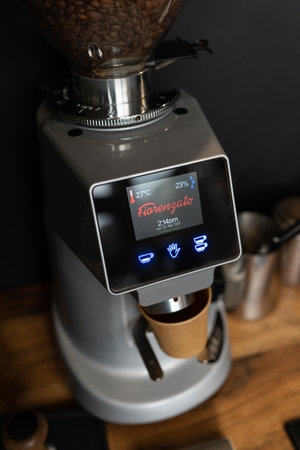 Close-up of a modern Fiorenzato coffee grinder with beans in the hopper. Digital touch screen shows temperature and settings. Professional barista equipment. Kyiv, Ukraine - January 26 2022のeditorial素材