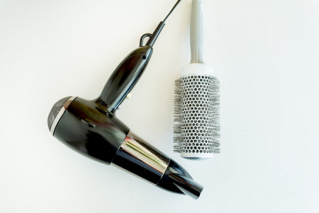 A black hairdryer and comb lie on the table after a hard day of working as a hairdresser. Hair care in the salonの写真素材