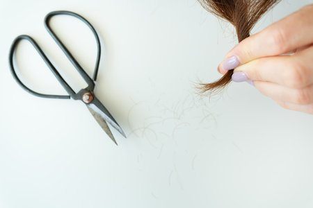 Hairdresser cuts brown hair with scissors. Haircut close-up. Getting rid of split ends, hair careの写真素材