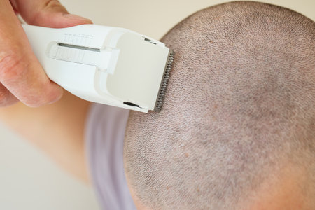 Close-up view of a person using an electric razor to shave their head, short buzz cut.の写真素材