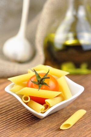 Raw penne pasta in a small bowl, selective focusの写真素材