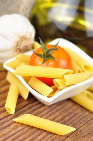 Raw penne pasta in a small bowl, selective focusの写真素材