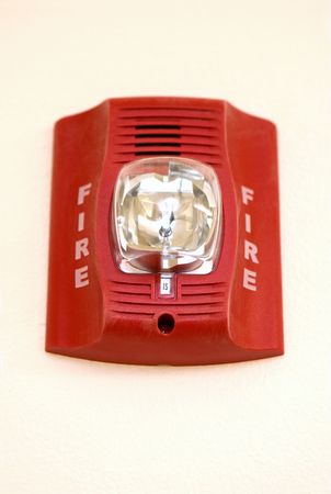 A red fire alarm hangs in an apartment building.