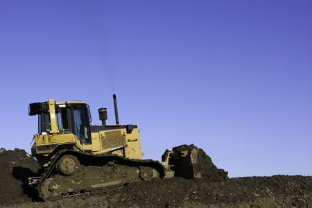 Bulldozer in operation moving dirt and clearing the land. Room for copy above.