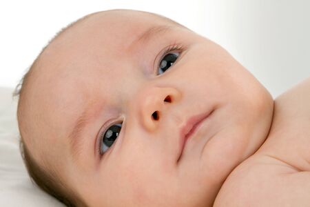 Close up of head of newborn baby on a white sheet.