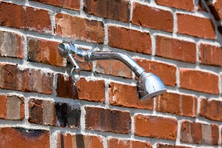 Outdoor shower head installed on a brick wall の写真素材