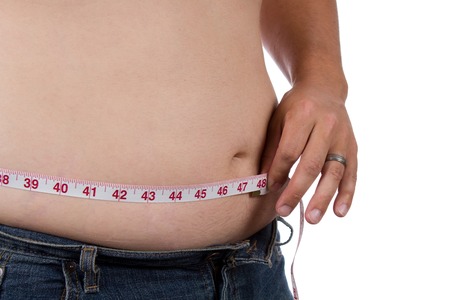Overweight man measures his waist size.