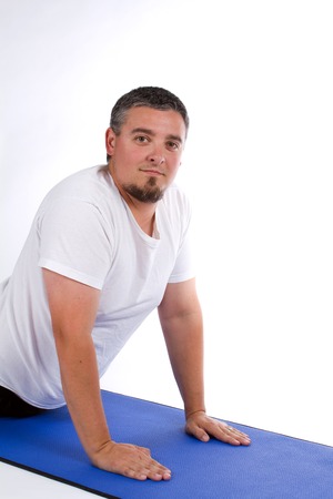 Overweight adult male stretches out in a yoga pose on a mat.の写真素材