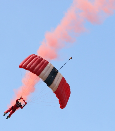 The Parachute Regiments Red Devils parachute display team display red smoke during a jump in England.のeditorial素材