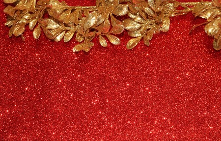 Sparkling gold leaves border a red glitter background with room for text.の写真素材