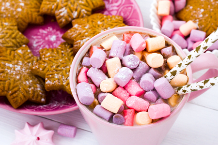 Christmas cocoa with marshmallow in a pink cup and ginger biscuit on a wooden tableの写真素材