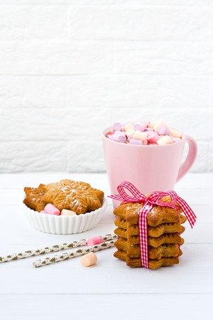 Christmas cocoa with marshmallow in a pink cup and ginger biscuit on a wooden tableの写真素材