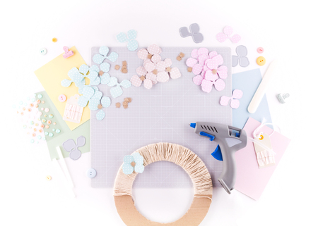 Flat lay, top view craft table desk. Workspace with mat for cutting, scissors, cardstock, paper, pencils on white background. Make floral wreath decor.の写真素材