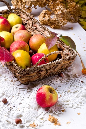 harvest of red apples in a basket and in autumn leavesの写真素材