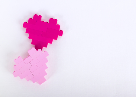 The bricks of the plastic constructor in the form of hearts are red, magenta, pink. White backgroundの写真素材