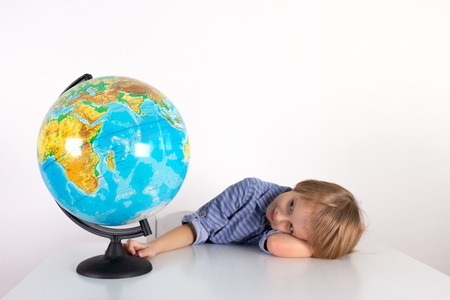 Toddler boy with a globe on the lesson of practical life on a white background, Montessori class, isolateの写真素材
