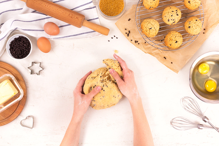Women's hands hold the dough for making cookies. Culinary equipment and ingredients. Eggs, flour, sugar, chocolate, butter, bakeware. Flat layの写真素材
