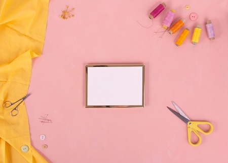 Flat lay of colored thread rolls and Scissors for sewing on pink tone background, Sewing and needlework concept. Copy spaceの写真素材