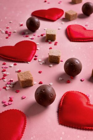 Red fabric hearts, sugar cubes, confetti, sweets candy chocolate on pink background. Valentines day 14 february love conceptの写真素材