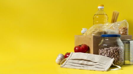 Banner.Donation. Food supplies crisis food stock for quarantine isolation period on yellow background. Rice, peas, cereals, canned food, oil, vegetables, mask, sanitizer. Food delivery. Cope space.の写真素材