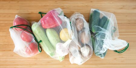 Fresh organic vegetables mushrooms in zero waste shopping bag on wooden table background flat layの写真素材