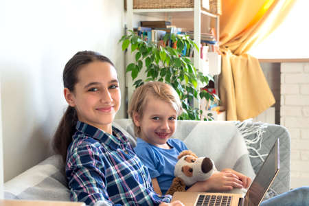 Distance learning online education and work. Child study remotely from home sits on the couch. Using mobile laptopの写真素材