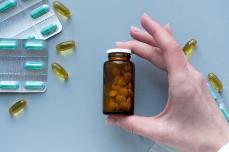 Womens hands hold a glass jar of pills antibiotics. Healthcare medical accessories therapy concept. Doctor workplace in hospital.の写真素材