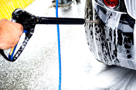 Close-up of man holding a high-pressure water sprayer for door car washing. Contactless self-service car wash. Concept disinfection and antiseptic cleaning of the vehicleの写真素材