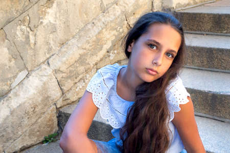 Portrait beautiful tanned caucasian girl against ancient stone wall. Attractive young tourist woman visiting city street old textured stone walls summer holiday, outdoors. Travel and lifestyleの写真素材