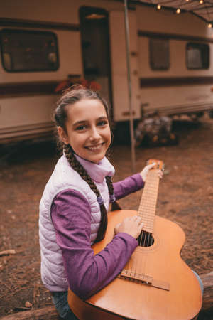 Happy family on a camping trip relaxing in the autumn forest. Camper trailer. Fall season outdoors tripの写真素材
