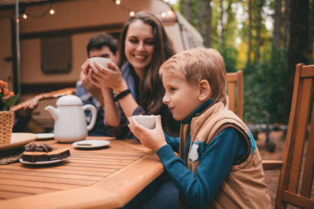 Happy family on a camping trip relaxing in the autumn forest. Camper trailer. Fall season outdoors tripの写真素材