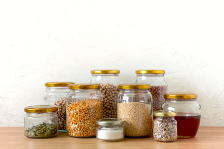Organic bio bulk products in zero waste shop. Foods storage in kitchen at low waste lifestyle. Cereals and grains in glass jars on table. Eco friendly shopping in plastic free grocery store.の写真素材