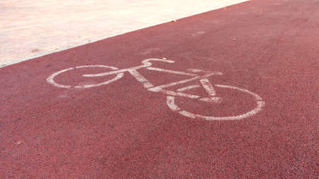 White painted sign for bikes on red bike path
