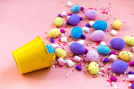 Decoration Happy Easter holiday background concept. Colorful bunny eggs in a yellow bucket on pink...