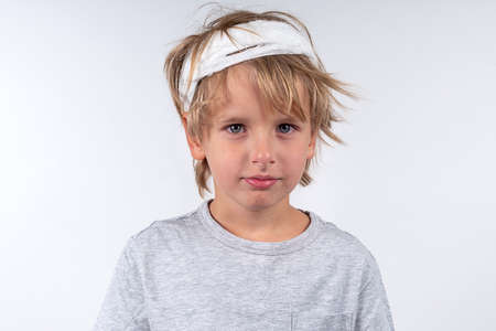 Portrait young caucasian cute boy blond hair with trauma injury and bandage head. Isolated on white background. Calm emotionsの写真素材